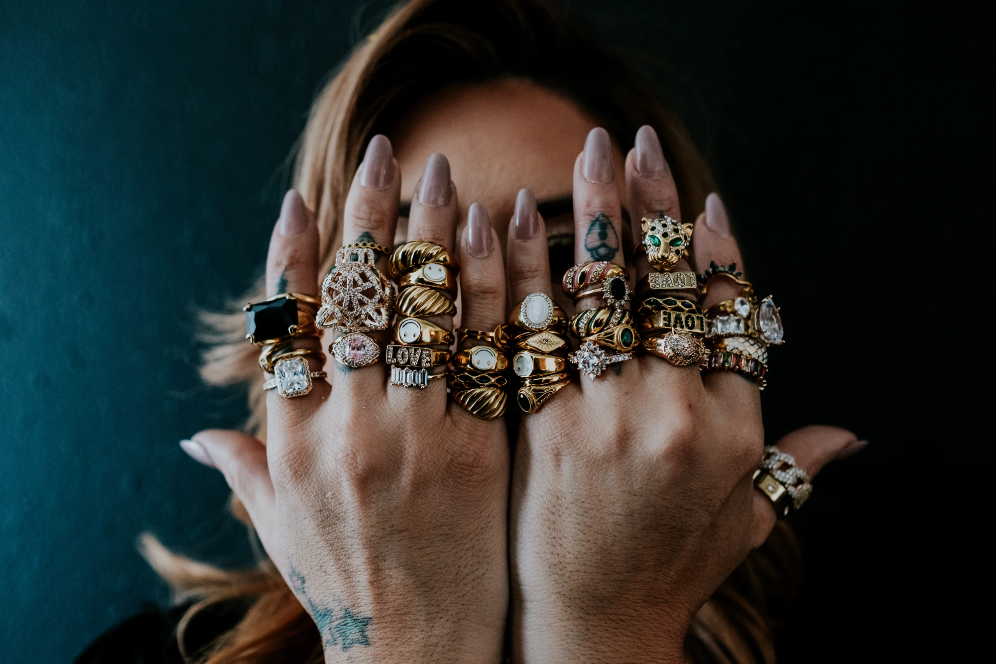 Hands stacked with gold rings, enamel smiley rings, stone rings and a leopard ring from Karizustyle in San Antonio